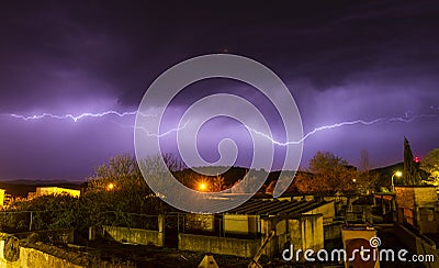 Lightning cracking during thunderstorm over houses of tiny town Stock Photo